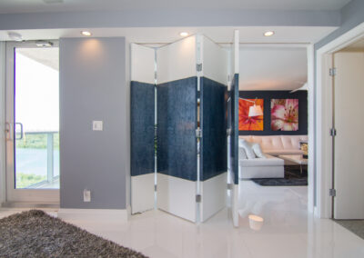 There is a blue and white divider that is folded enough to see part of the living room. There is a glass door on the left that shows some of the view.