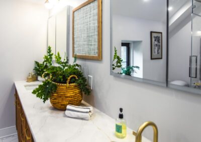 A white countertop in the primary bathroom with brass hardware and textured wooden cabinets